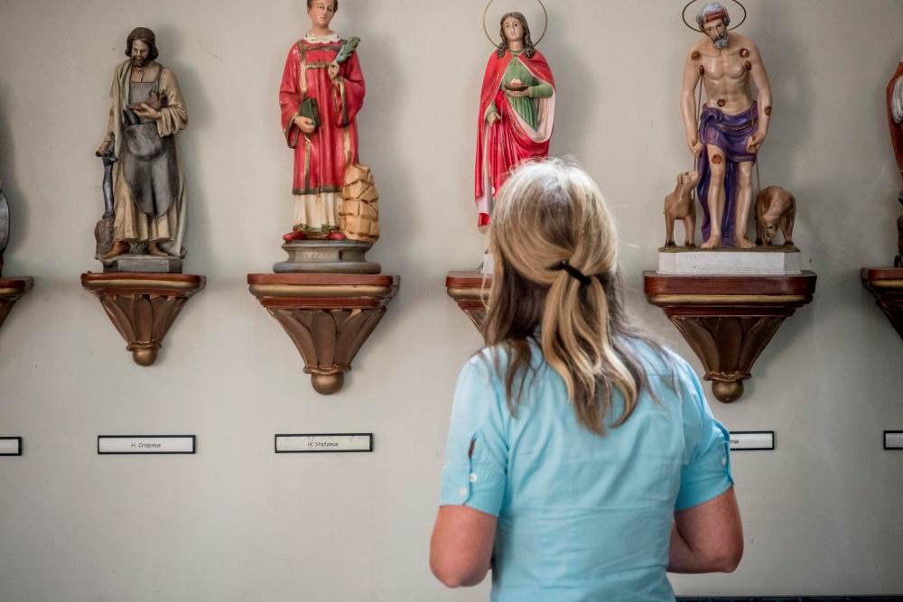 Vrouw kijkt naar heiligenbeelden in de kerk