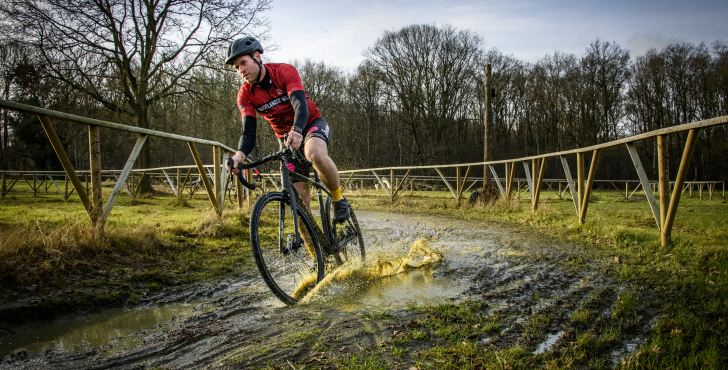 Fietser door modder op een cyclocross fiets van Trek