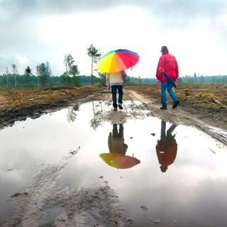 Wandelaars weerspiegeld in een regenplas